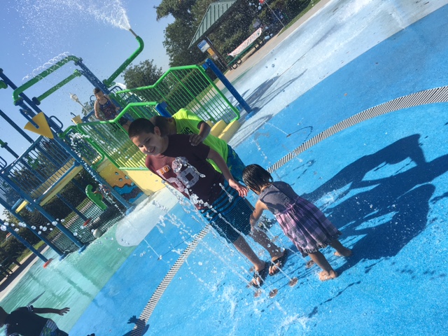 Two boys and a little girl playing in a fountain