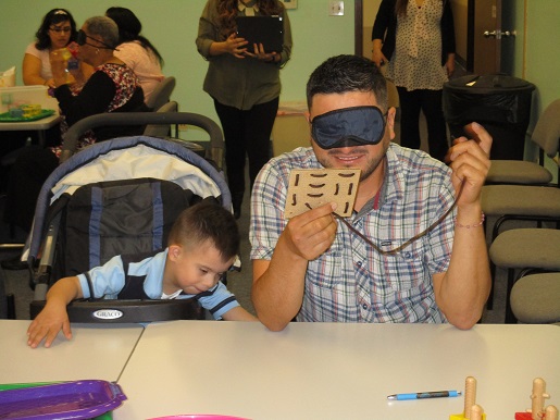 A father is blindfolded and is experiencing the challenges his child is now facing.
