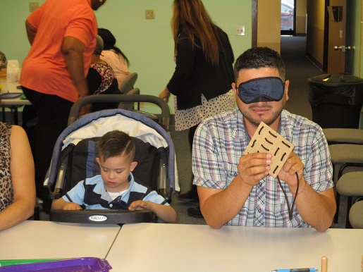A father is blindfolded and is experiencing the challenges his child is now facing.
