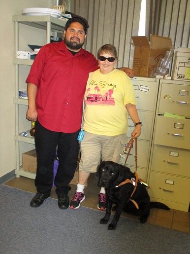 Luis and Teresa are standing with Chuck the guide dog