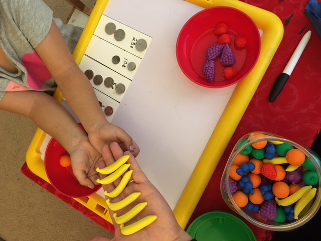 A Blind child is learning to count with plastic fruit