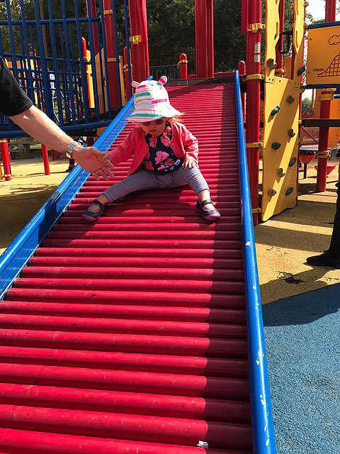 A child is sliding down the slid at the sensory playground at Fairmount Park