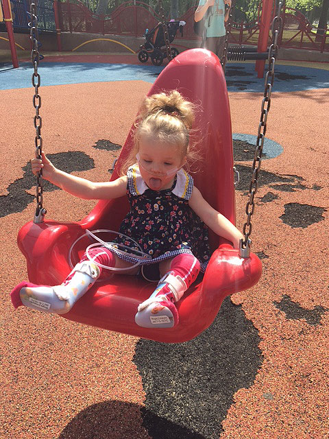 A child is sitting on a swing in the sensory playground at Fairmount Park