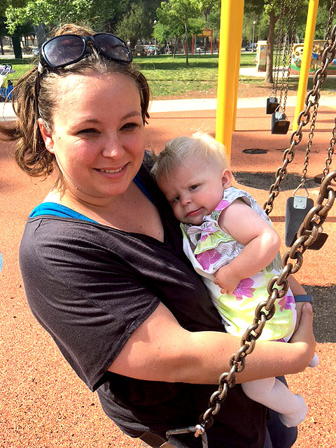 A mother and her baby are sitting on a swing at Park Day