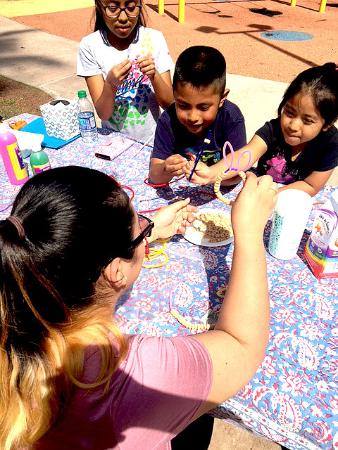 Children are putting tactile beads on to a fuzzy pipe cleaner at Park Day