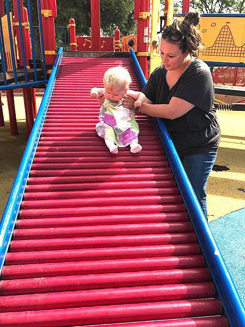 A mother is playing with her child on the slide at Park Day