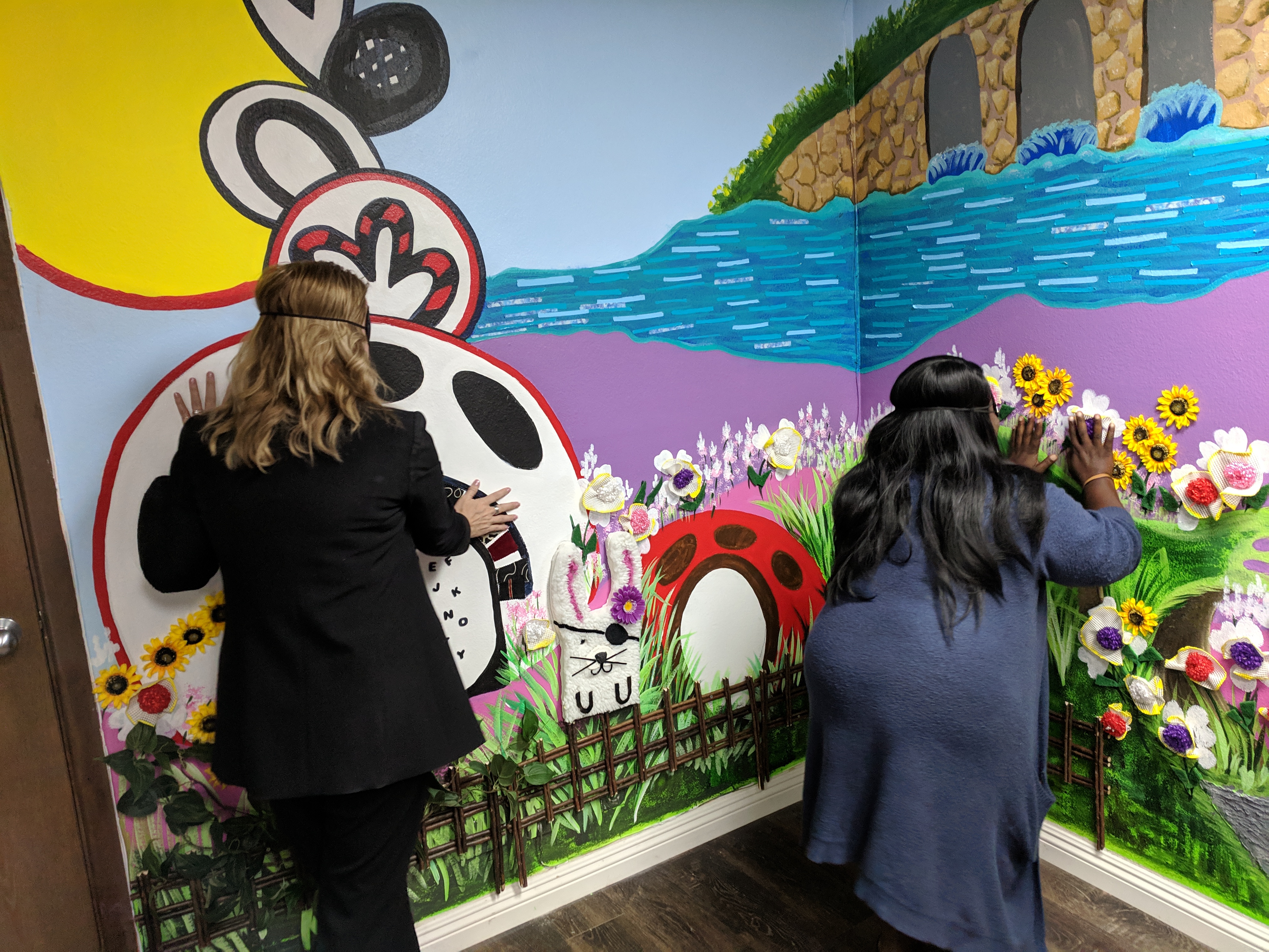 two women feeling the left side of the mural