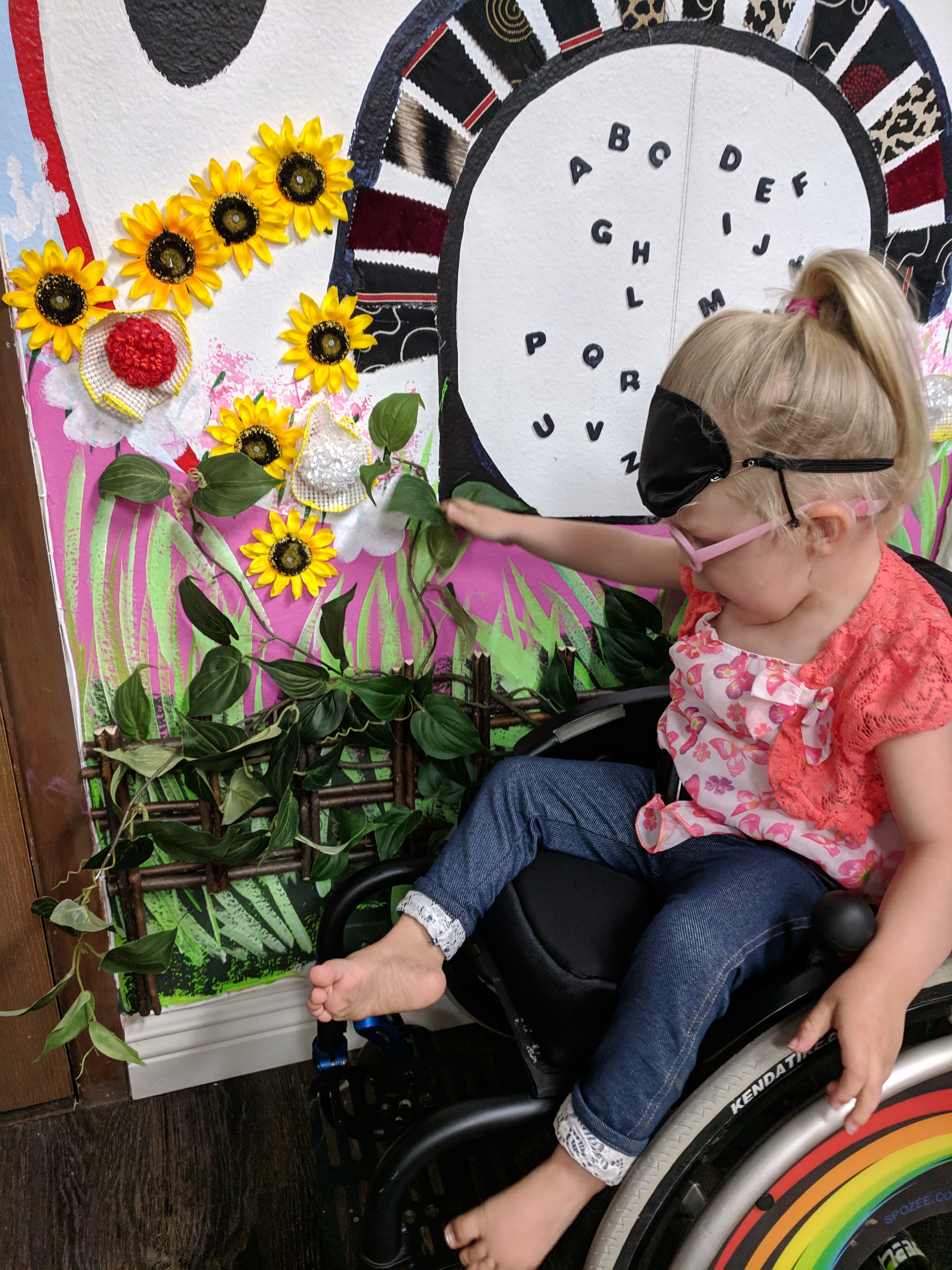 a wheelchair bound girl feeling flowers on the left side of our mural