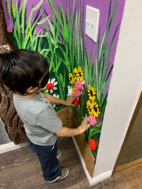 a little boy blindfolded and feeling the flowers on the tactile mural