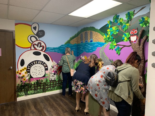 a group of five women feeling all around the tactile mural